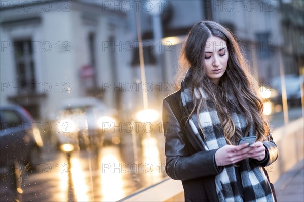 Serious Caucasian woman texting on cell phone outdoors
