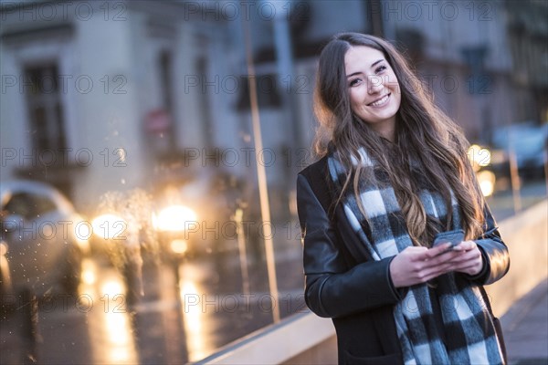 Smiling Caucasian woman texting on cell phone outdoors