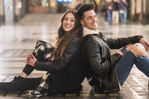 Caucasian couple sitting back to back on lobby floor