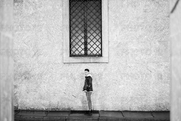 Portrait of distant man standing underneath window on sidewalk