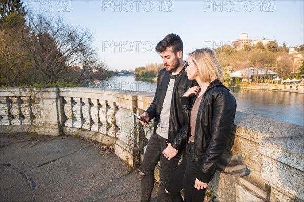 Caucasian couple texting on cell phone near river