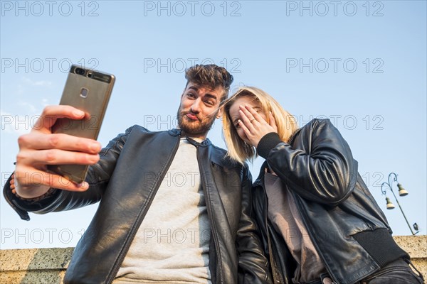 Caucasian couple posing for cell phone selfie