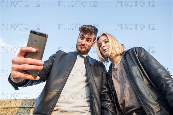 Caucasian couple posing for cell phone selfie