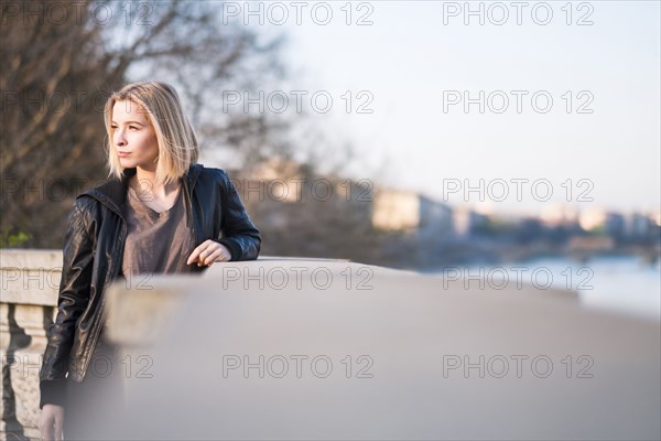 Caucasian woman leaning on wall near river