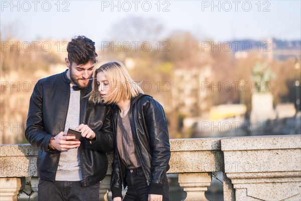 Caucasian couple texting on cell phone outdoors