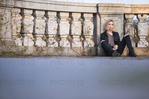 Caucasian woman sitting on ground leaning on wall