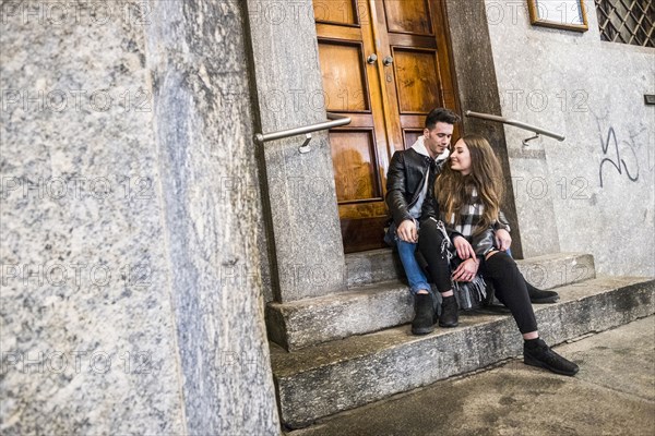 Caucasian couple sitting on concrete front stoop
