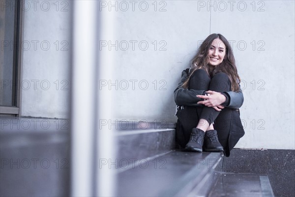 Smiling Caucasian woman sitting on staircase