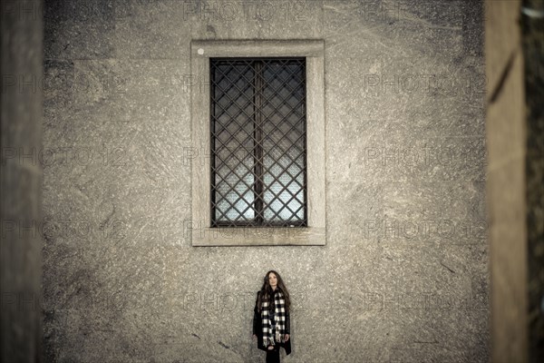 Portrait of Caucasian woman standing under window
