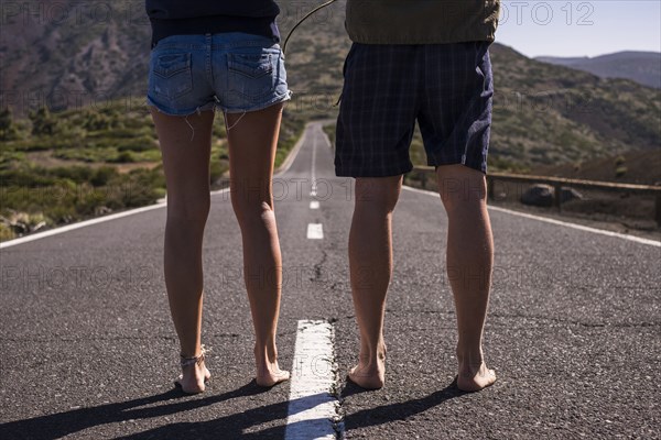 Legs of barefoot Caucasian couple standing in middle of road