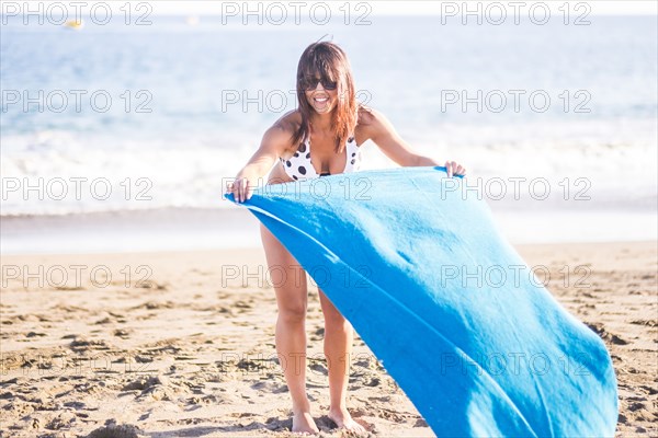 Caucasian woman spreading blanket on beach