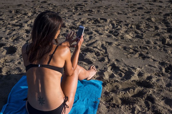 Caucasian woman texting on cell phone on beach