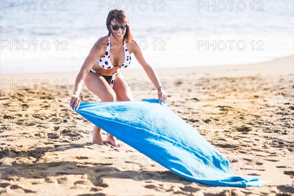 Caucasian woman spreading blanket on beach