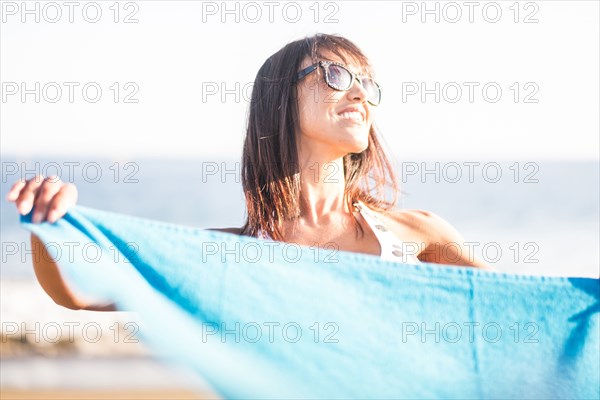 Caucasian woman holding blanket on beach