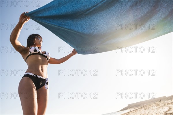 Caucasian woman spreading blanket on beach