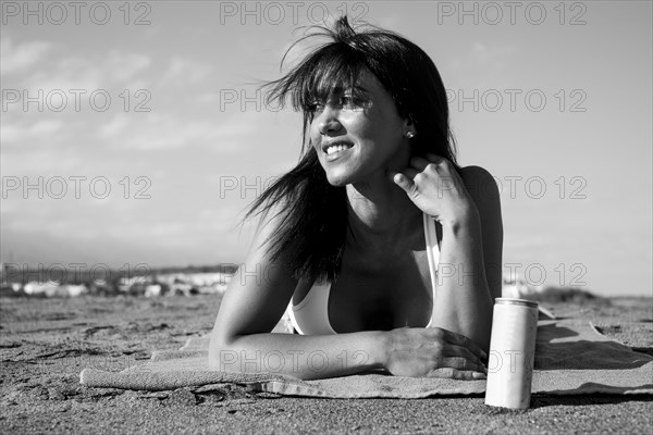 Caucasian woman laying on beach with can