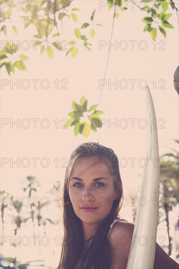 Portrait of Caucasian woman holding surfboard