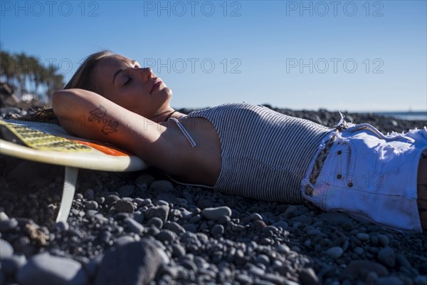 Caucasian woman laying on surfboard on beach