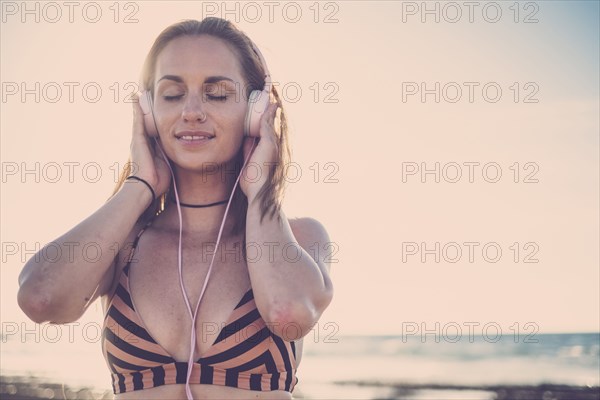 Caucasian woman listening to headphones on beach