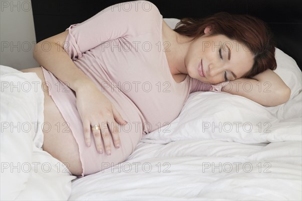 Pregnant Hispanic woman napping in bed