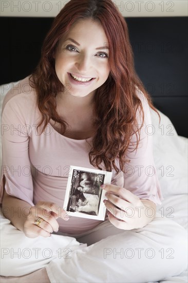 Pregnant Hispanic woman holding sonogram picture