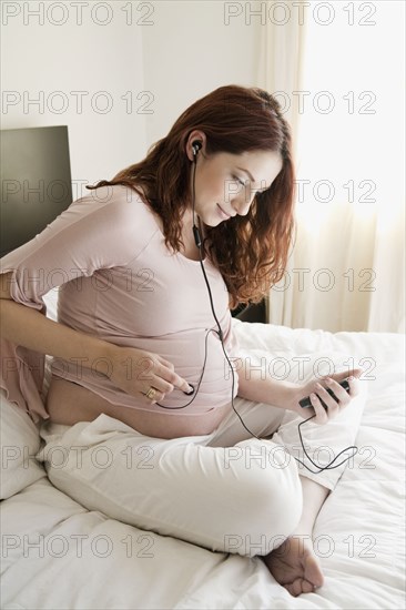Pregnant Hispanic woman playing music for unborn baby