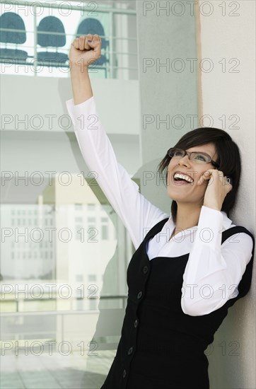 Hispanic woman cheering and talking on cell phone