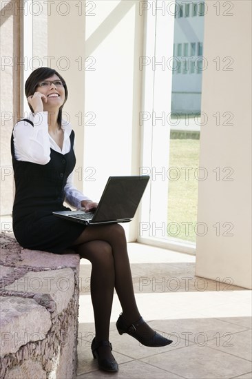 Hispanic businesswoman using laptop outdoors