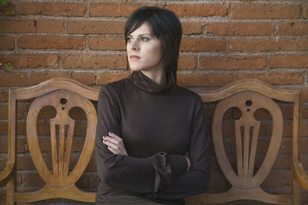 Frustrated Hispanic woman sitting on bench