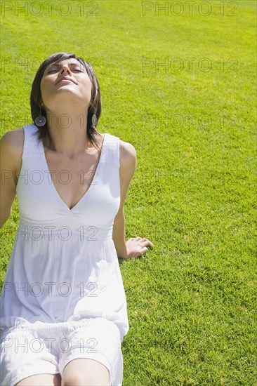 Hispanic woman relaxing on grass