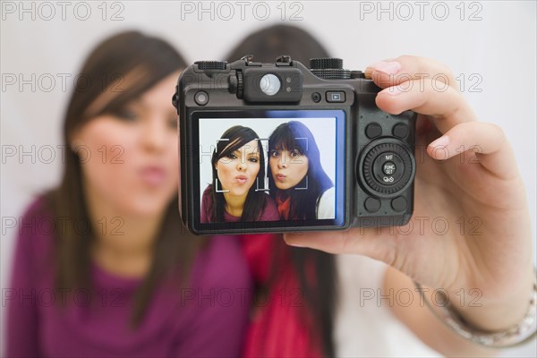 Hispanic friends taking self-portrait with digital camera