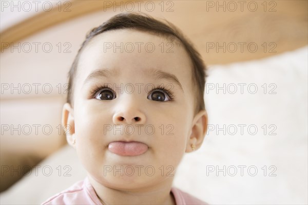 Hispanic baby girl sticking out tongue