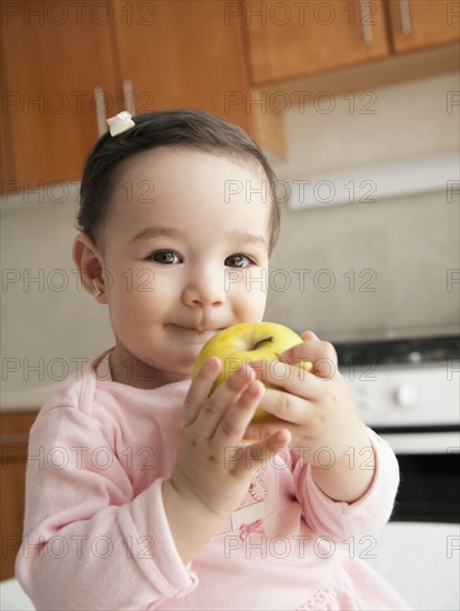Hispanic baby girl eating apple
