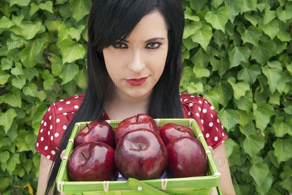 Hispanic woman holding basket of apples