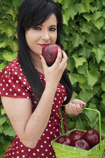Hispanic woman holding basket of apples