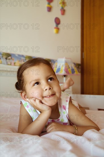 Hispanic girl daydreaming on bed