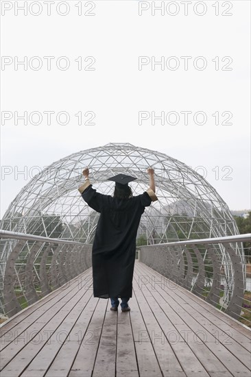 Mixed race graduate in cap and gown cheering