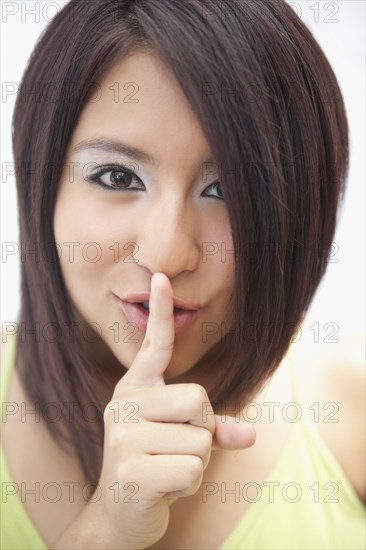 Hispanic teenage girl making shhh gesture