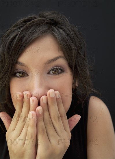 Surprised Hispanic woman with hands covering face