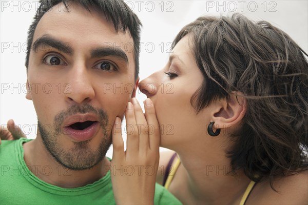 Hispanic woman whispering to boyfriend