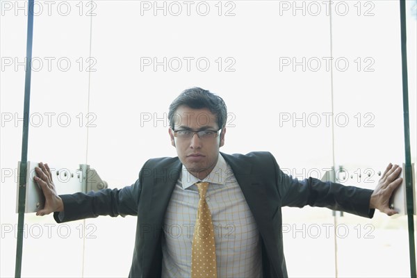 Frowning Hispanic businessman opening doors