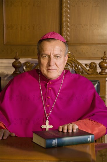 Hispanic bishop sitting with bible