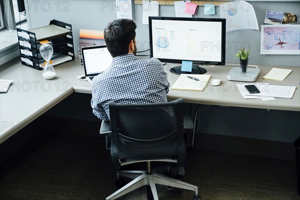 Caucasian businessman using laptop and computer in office