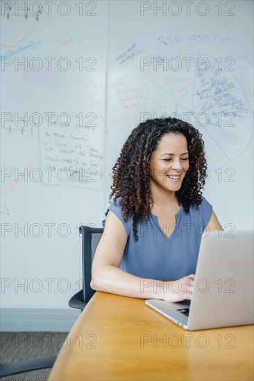 Mixed race businesswoman using laptop