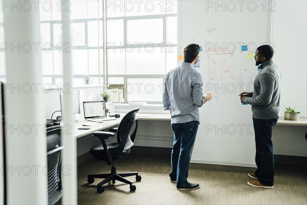 Businessmen using whiteboard in office