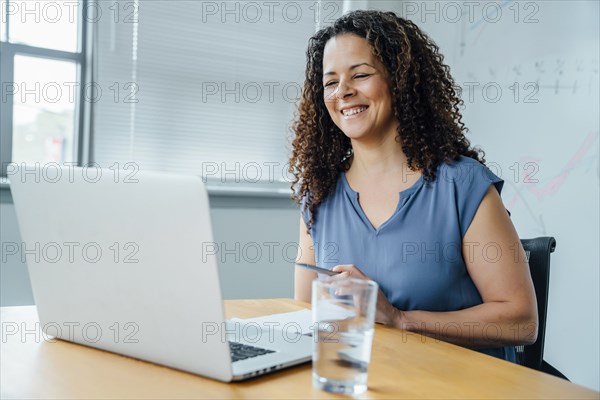 Mixed race businesswoman smiling at laptop