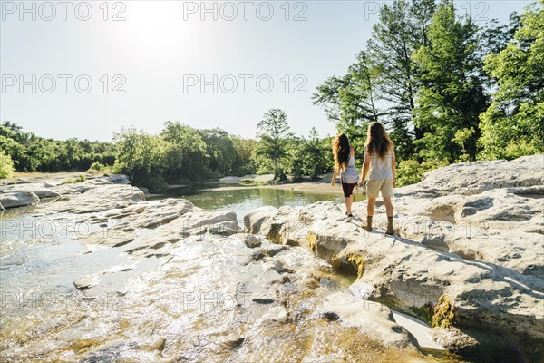 Caucasian couple walking on rocks near river