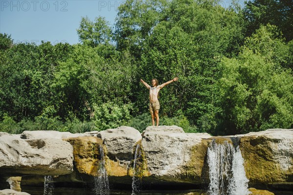 Caucasian man standing on rocks near waterfalls