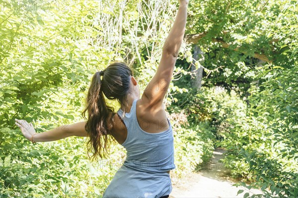 Caucasian woman stretching arms near trees