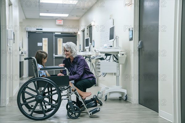 Smiling doctor comforting girl in wheelchair